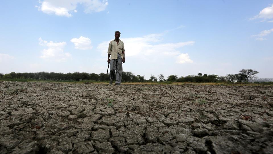 Ein indischer Bauer geht über ausgetrockneten Boden. | Bildquelle: dpa